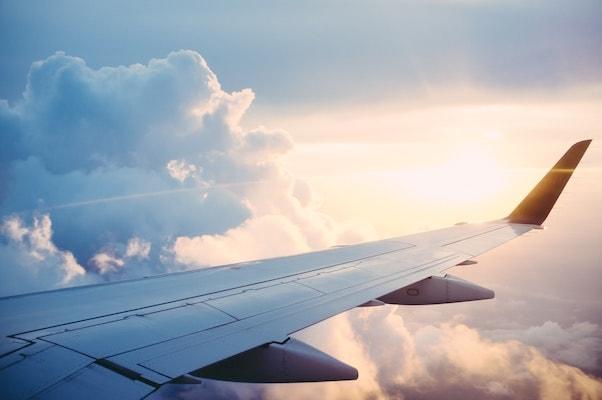 view of the plane's wing with the sun on the horizon from the perspective of the plane's window